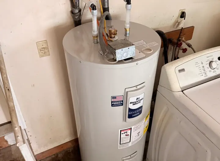 Tank water heater installed in a laundry room by Crest Plumbing
