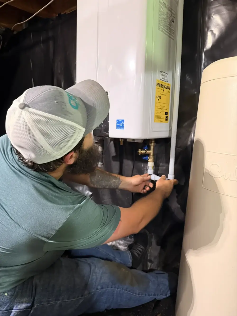 A Crest Plumbing technician connecting the water lines on a new tankless water heater