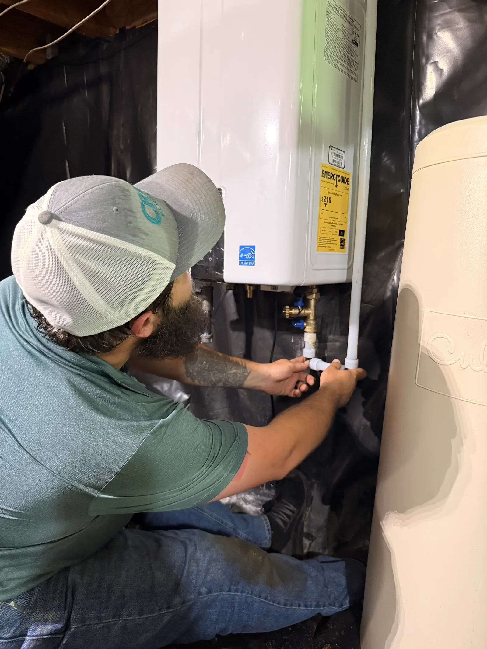 A Crest Plumbing technician connecting the water lines on a new tankless water heater