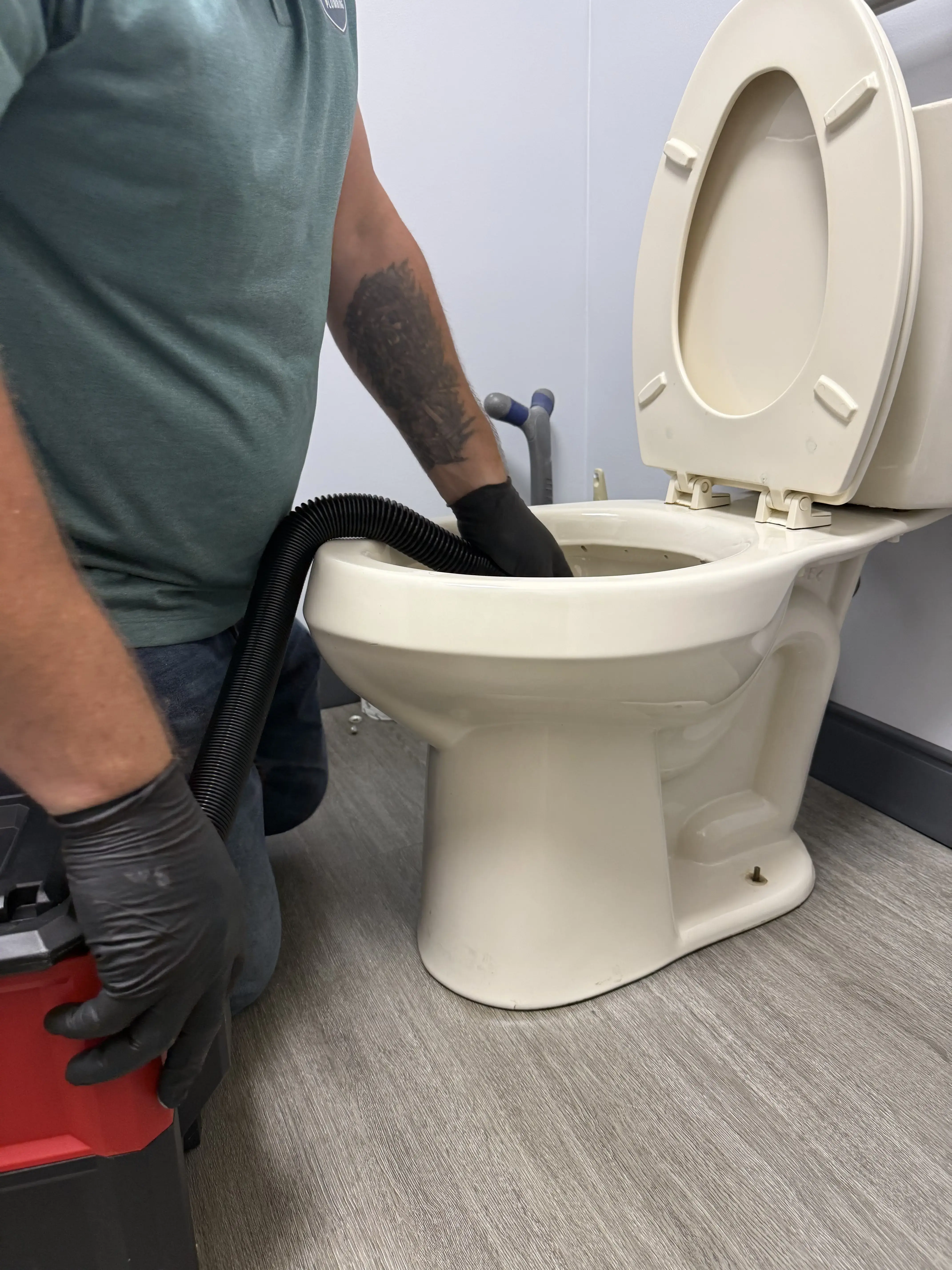 Crest Plumbing technician clearing a toilet with service equipment