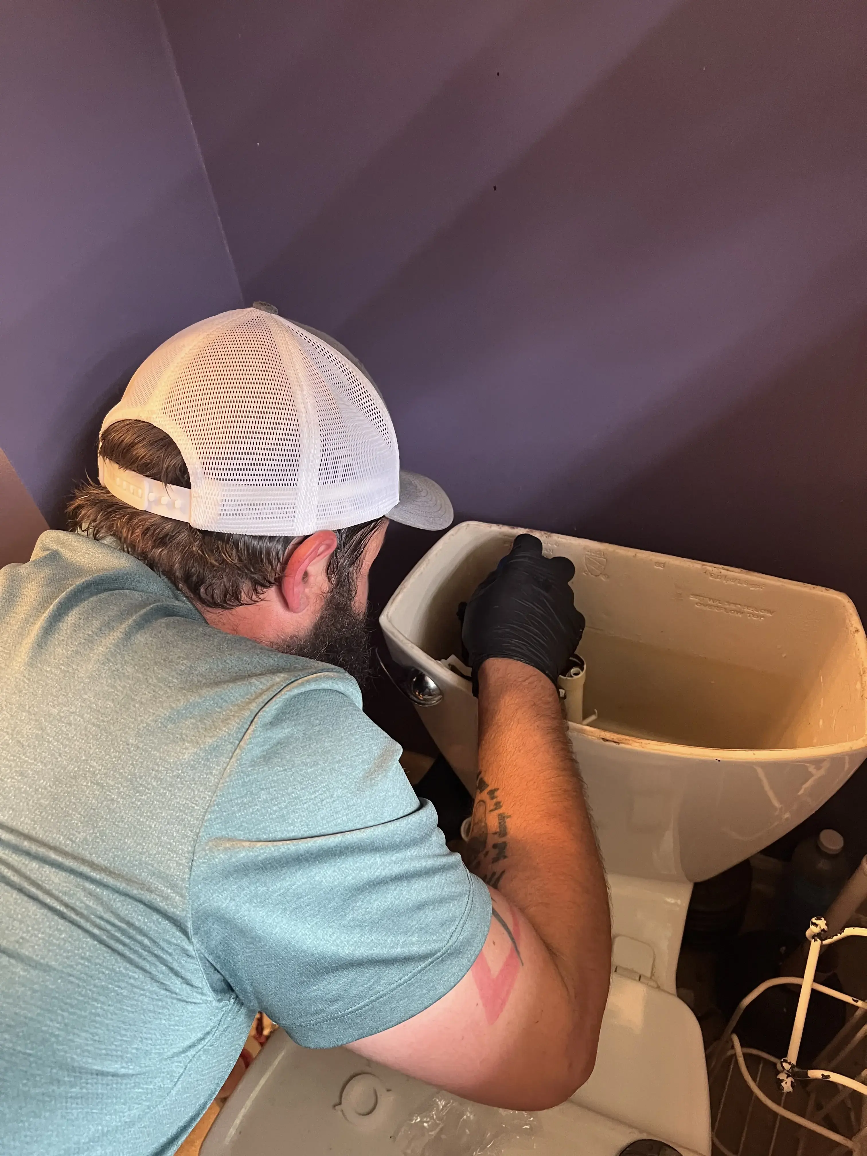Crest Plumbing technician repairing parts inside a toilet tank