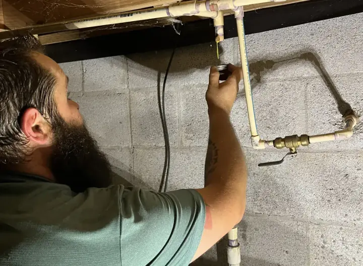 Crest Plumbing technician working on a crawlspace water line connection